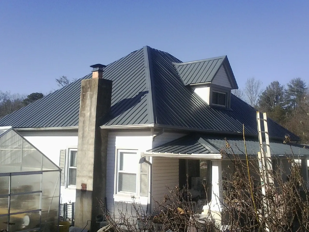 Dark blue standing seam metal roof on a white farmhouse with dormer — Slate & Tile Roof Repair by Roofing Brothers in Hazel Crest