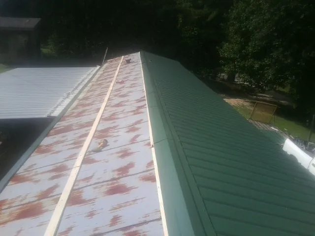 Old rusted panels beside newly installed green metal roofing — Wind Damage Roof Repair by Roofing Brothers in Hazel Crest