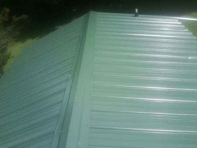 New green metal panels meeting at the ridge of a roof — Flat Roof Repair work by our crew in Hazel Crest