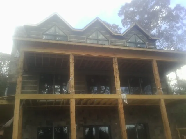 Dormers and porch framing on a large log home under construction — Roof Coating work by our crew in Hazel Crest