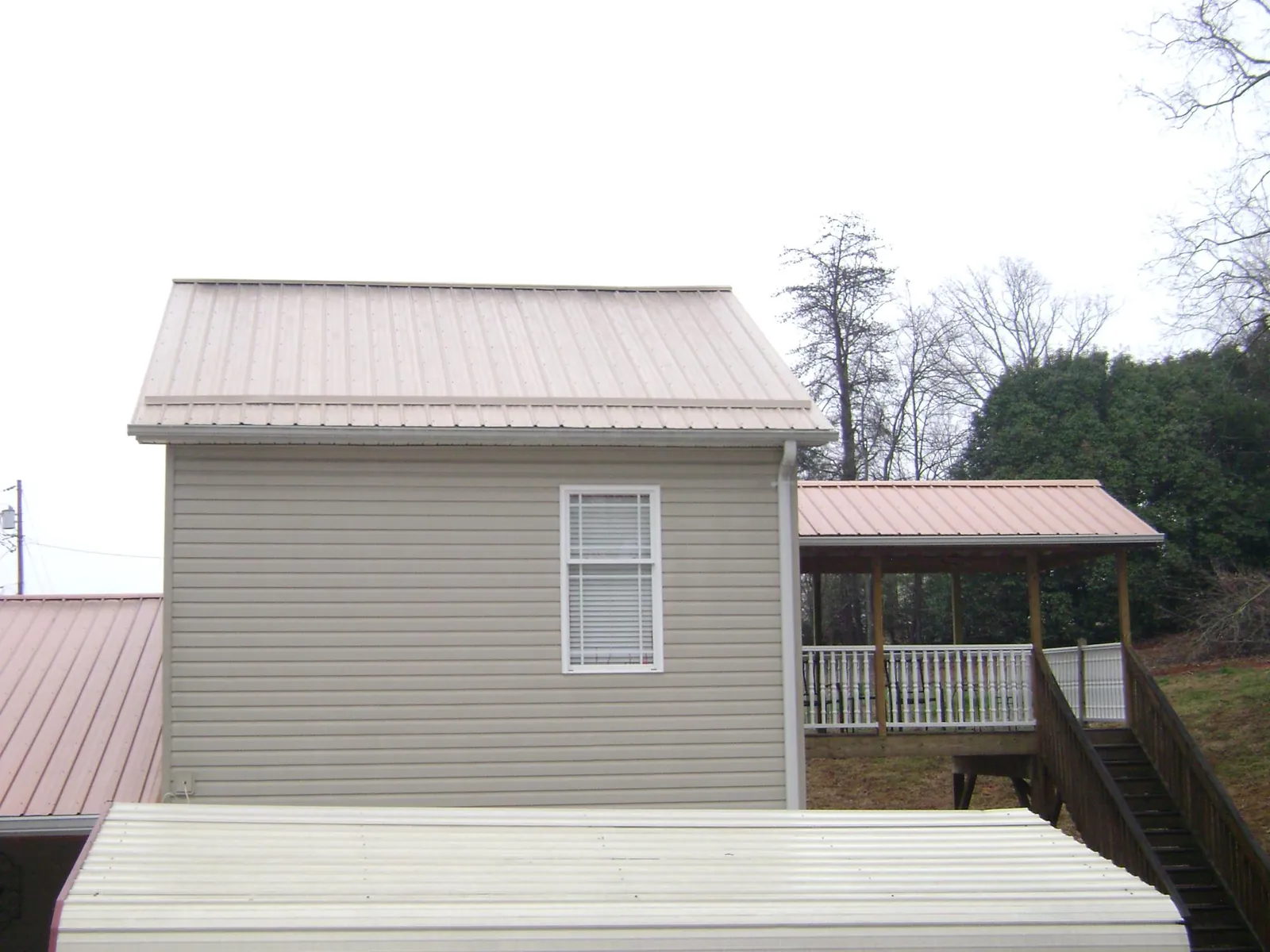 Tan metal roofs on a two story addition and attached porch, from a Roof Replacement job in Hazel Crest