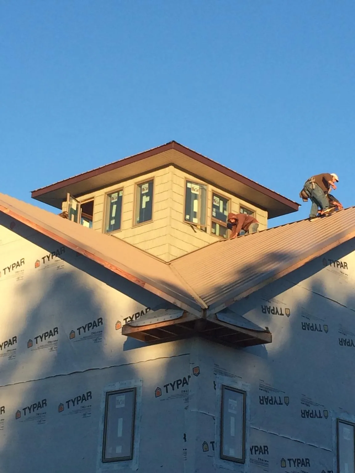 Roofers working around a rooftop cupola on a new metal roof at sunset — Roof Waterproofing in Hazel Crest by Roofing Brothers